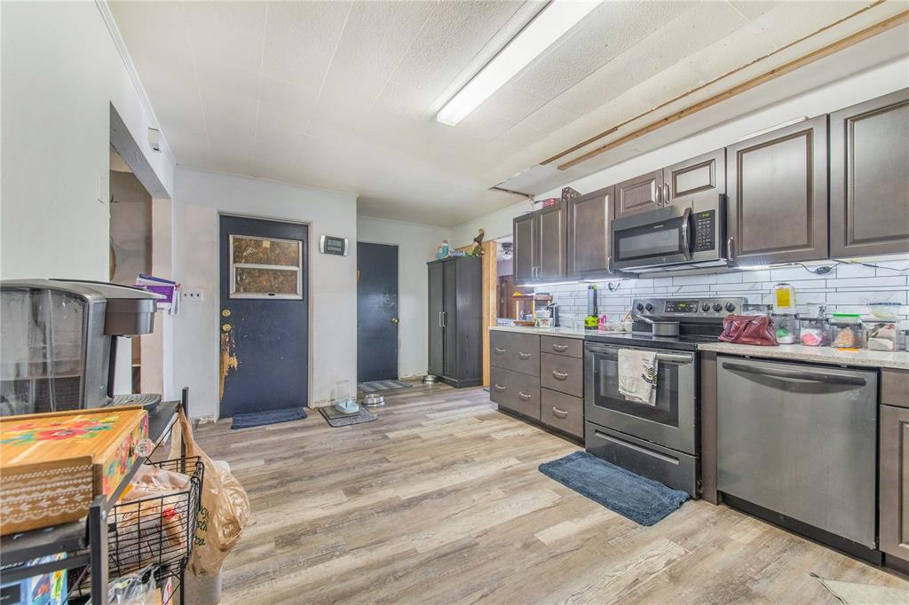 A kitchen features dark wood cabinets, stainless steel appliances, and wood-look flooring — 400 E POMELO STREET, LAKE ALFRED, FL