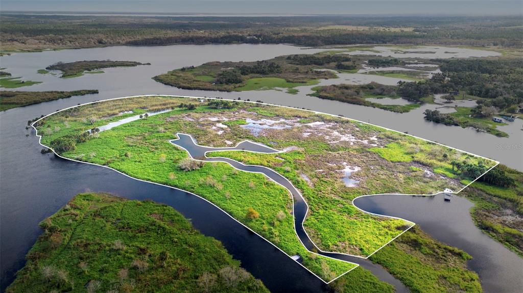An aerial view shows a marshy island surrounded by water with a white property boundary outline — NO NAME, OSTEEN, FL