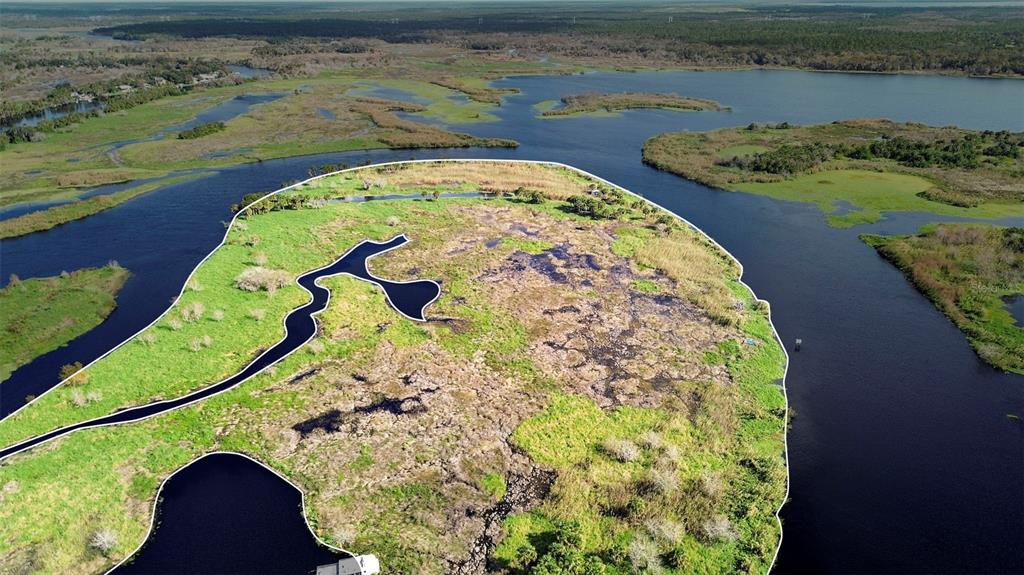 An aerial view shows a marshy island surrounded by a river and wetlands — NO NAME, OSTEEN, FL
