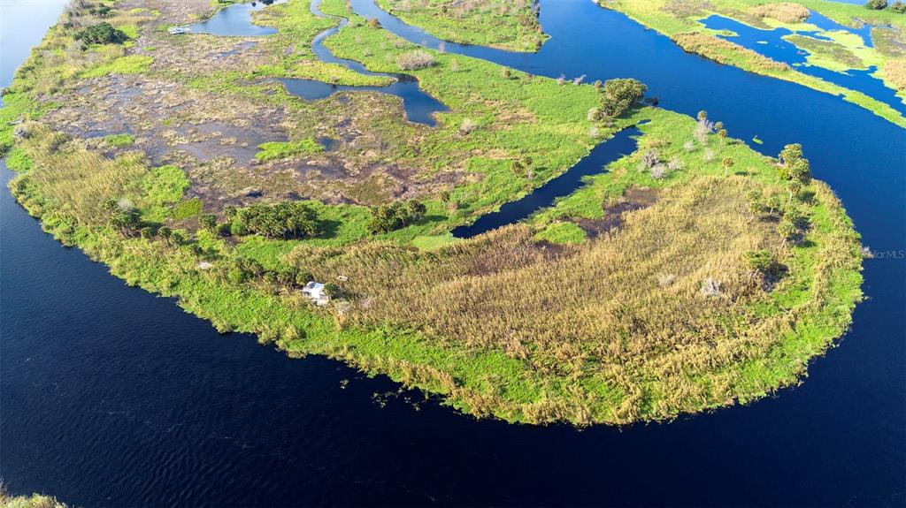 An aerial view shows a small structure situated on a grassy island surrounded by water — NO NAME, OSTEEN, FL