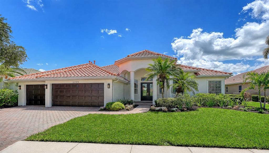 The exterior of a single-story house features a tiled roof, a garage, and a palm tree — 2729 HARVEST DRIVE, SARASOTA, FL