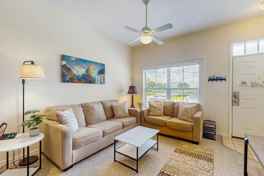 A living room features beige sofas, a white coffee table, and a ceiling fan — 2200 SAN VITTORINO CIRCLE UNIT 105, KISSIMMEE, FL
