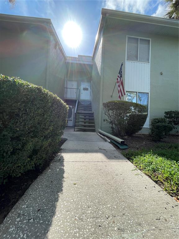 A concrete walkway leads to an outdoor staircase between two light green apartment buildings — 586 BAHIA CIRCLE UNIT B, OCALA, FL