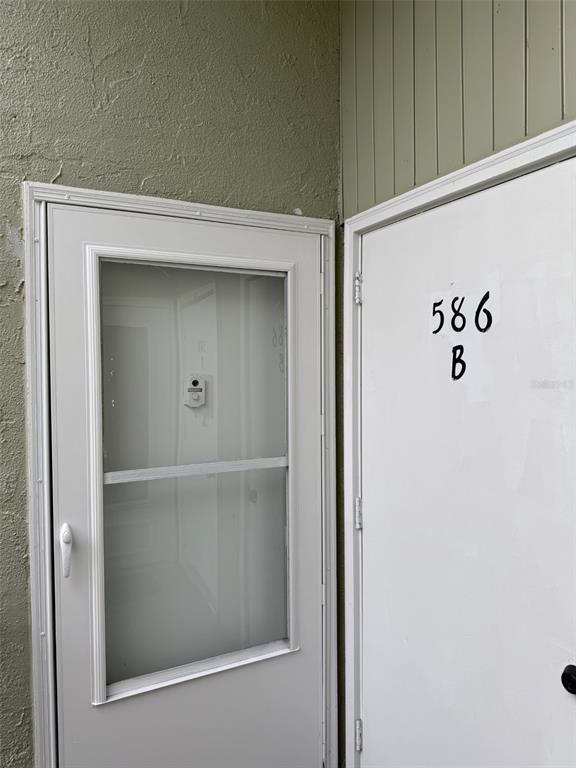 A white door labeled 586 B sits next to a white storm door with a screen — 586 BAHIA CIRCLE UNIT B, OCALA, FL