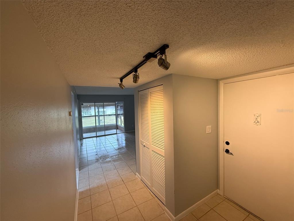 An entryway with tile flooring leads to a living area with sliding glass doors — 586 BAHIA CIRCLE UNIT B, OCALA, FL