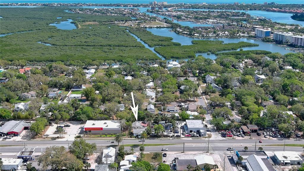 An aerial view shows a commercial building with a white arrow pointing to a house — 607 N DIXIE FREEWAY, NEW SMYRNA BEACH, FL