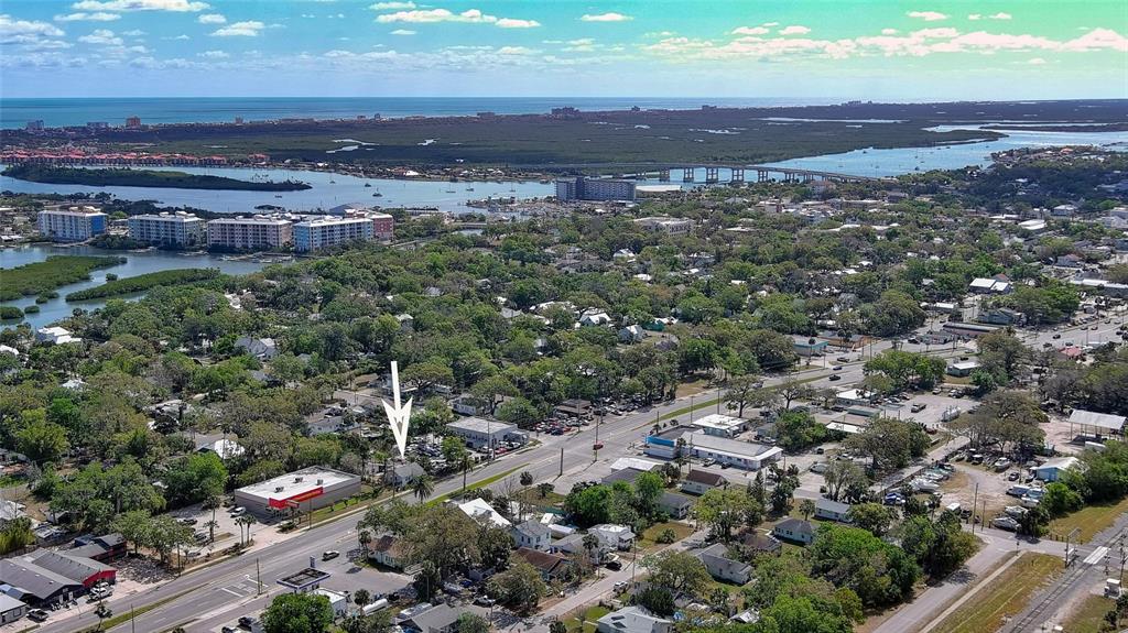 An aerial view shows a small house marked with an arrow near a commercial street — 607 N DIXIE FREEWAY, NEW SMYRNA BEACH, FL