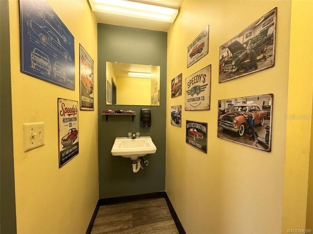 A small bathroom features yellow walls, a wall-mounted sink, and automotive-themed wall decor — 8 HIGHWAY 19 N, INGLIS, FL