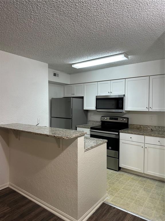 A living room features wood-look flooring, a media console, a bookshelf, and a tall display rack — 2214 METROPOLITAN WAY UNIT 1022, ORLANDO, FL