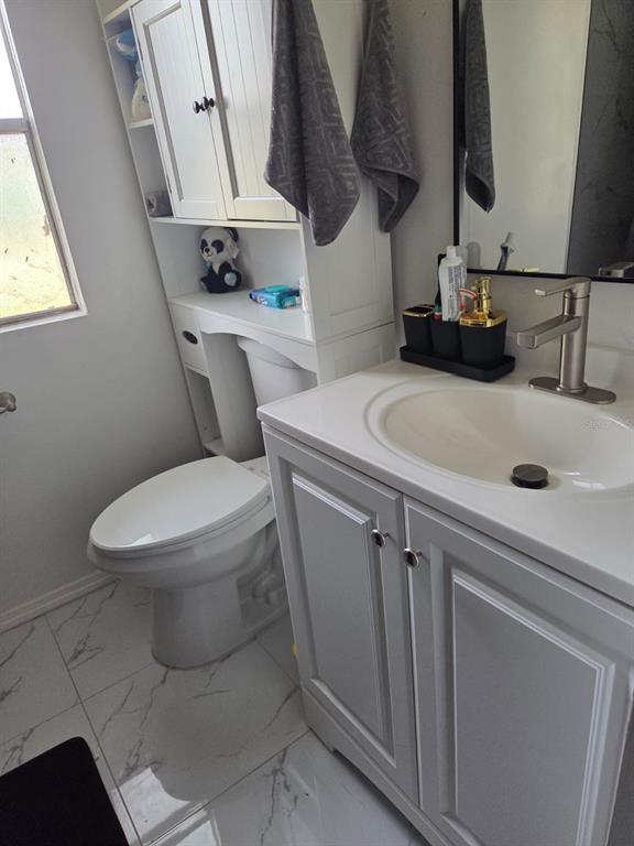 A bathroom features a white vanity, a toilet, and an over-the-toilet storage unit — 18341 12TH AVENUE, ORLANDO, FL
