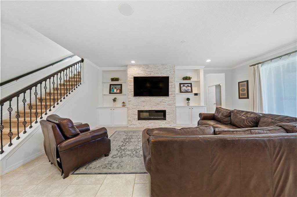 A living room features a stone fireplace, built-in shelving, a leather sectional, and a staircase — 2202 REDMARK LANE, WINTER GARDEN, FL