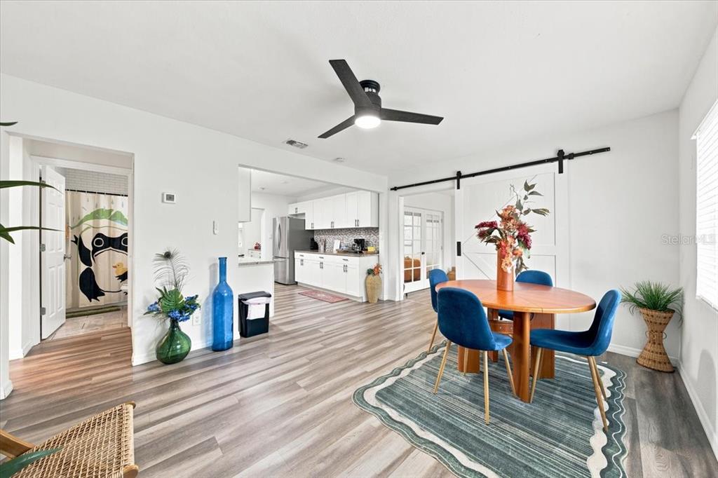 A dining area with a wooden table, blue chairs, and a sliding barn door — 6350 60TH AVENUE N, ST PETERSBURG, FL