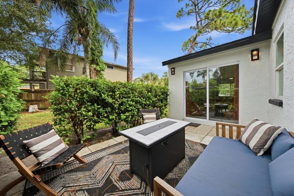 A patio features a fire pit table, outdoor seating, and a patterned rug near a house — 6350 60TH AVENUE N, ST PETERSBURG, FL