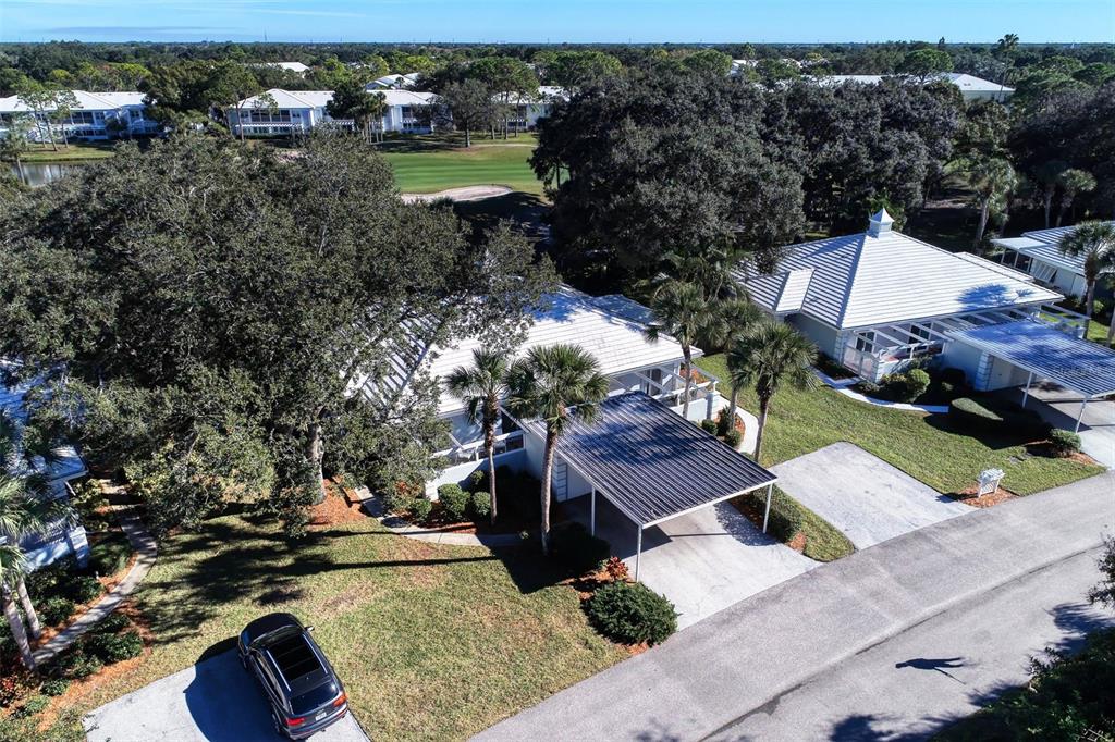 An aerial view shows a house with a metal carport and a white tile roof — 216 CERROMAR WAY S UNIT 30, VENICE, FL