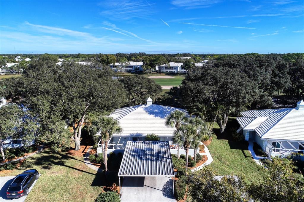 An aerial view shows a house with a white roof, a carport, and surrounding trees — 216 CERROMAR WAY S UNIT 30, VENICE, FL
