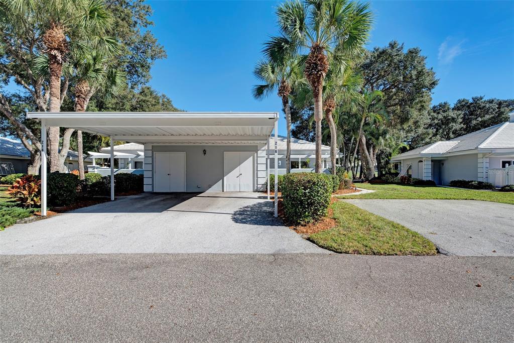 A white carport with two storage doors sits in front of a single-story residential building — 216 CERROMAR WAY S UNIT 30, VENICE, FL