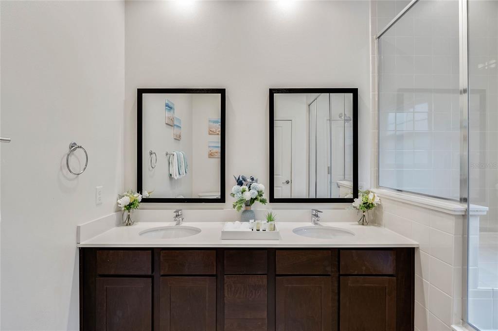 A bathroom features a double vanity with dark wood cabinets, white countertops, and two mirrors — 5710 OLGA STREET, KISSIMMEE, FL