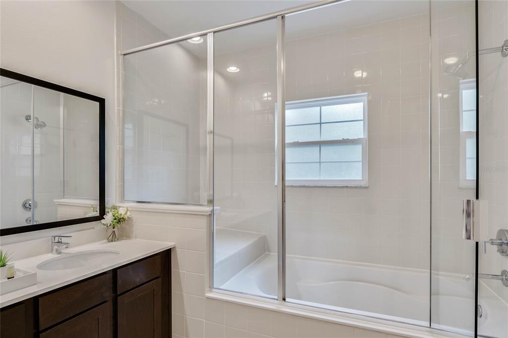 A bathroom features a dark wood vanity, a white countertop, and a tiled tub-shower combination — 5710 OLGA STREET, KISSIMMEE, FL