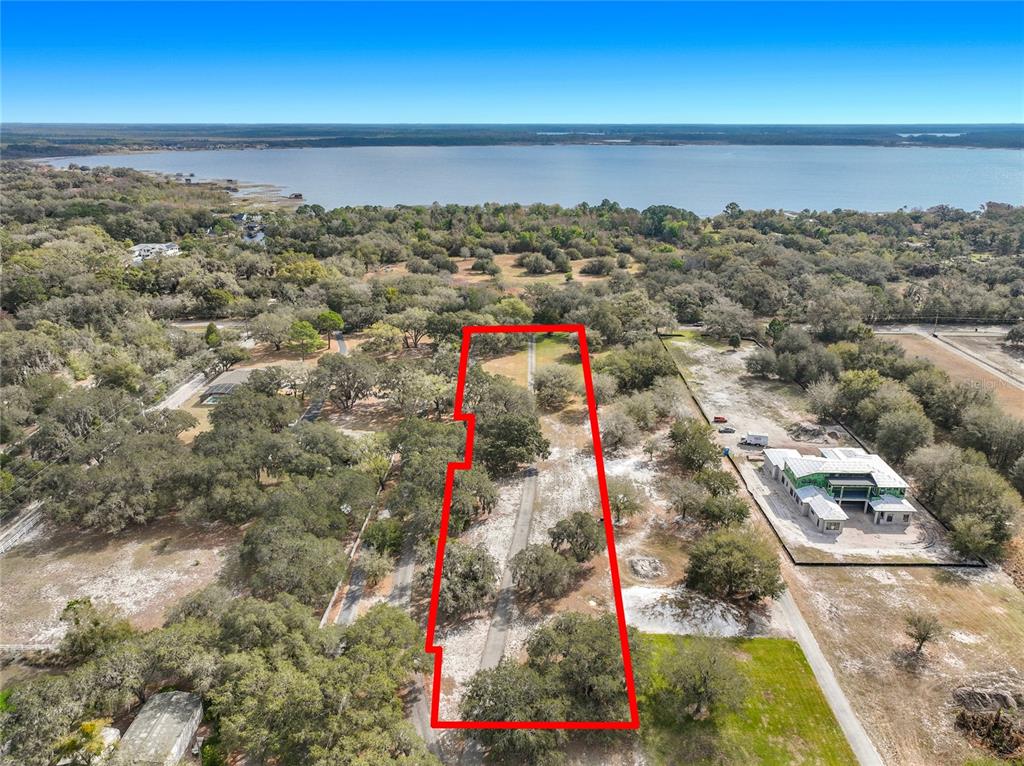 An aerial view shows a rectangular plot of land outlined in red near a lake — KIRBY SMITH ROAD, ORLANDO, FL