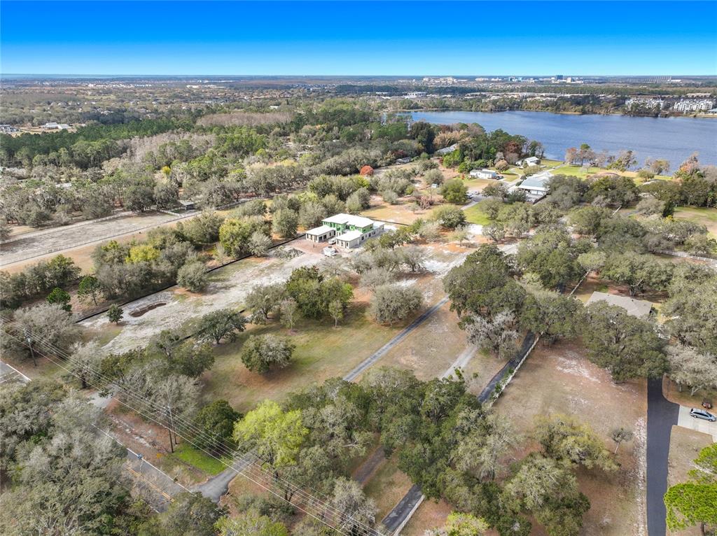An aerial view shows a large, partially constructed house on a wooded lot near a lake — KIRBY SMITH ROAD, ORLANDO, FL
