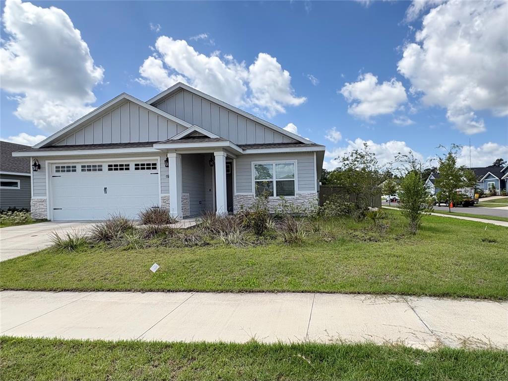 A single-story house with light gray siding, a stone base, and a two-car garage — 6737 SW 13TH LANE, GAINESVILLE, FL
