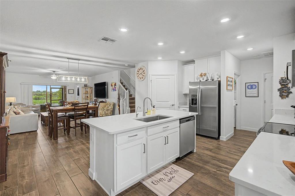 A white kitchen island with a sink sits in an open-concept room with wood-look flooring — 32172 CANNON RUSH DRIVE, SAN ANTONIO, FL