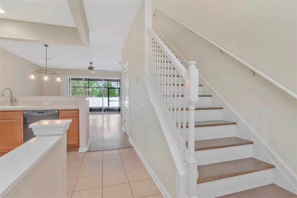 A staircase with white railings and wood treads sits beside a kitchen with tile flooring — 10208 ESTERO BAY LANE, TAMPA, FL