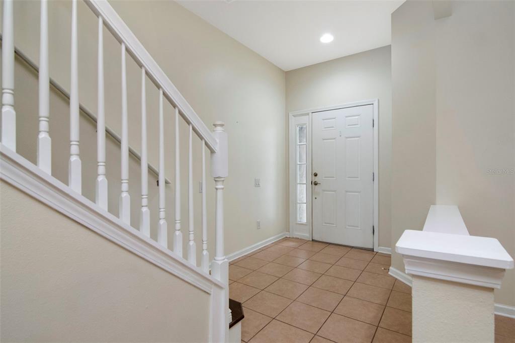 An entryway features a white staircase, a white front door, and light-colored tile flooring — 10208 ESTERO BAY LANE, TAMPA, FL