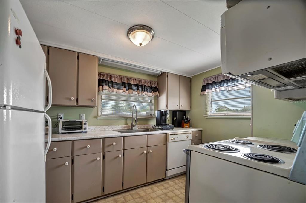 A kitchen features brown cabinets, light countertops, a white stove, and a white refrigerator — 122 E SAINT ANNES CIRCLE, APOLLO BEACH, FL