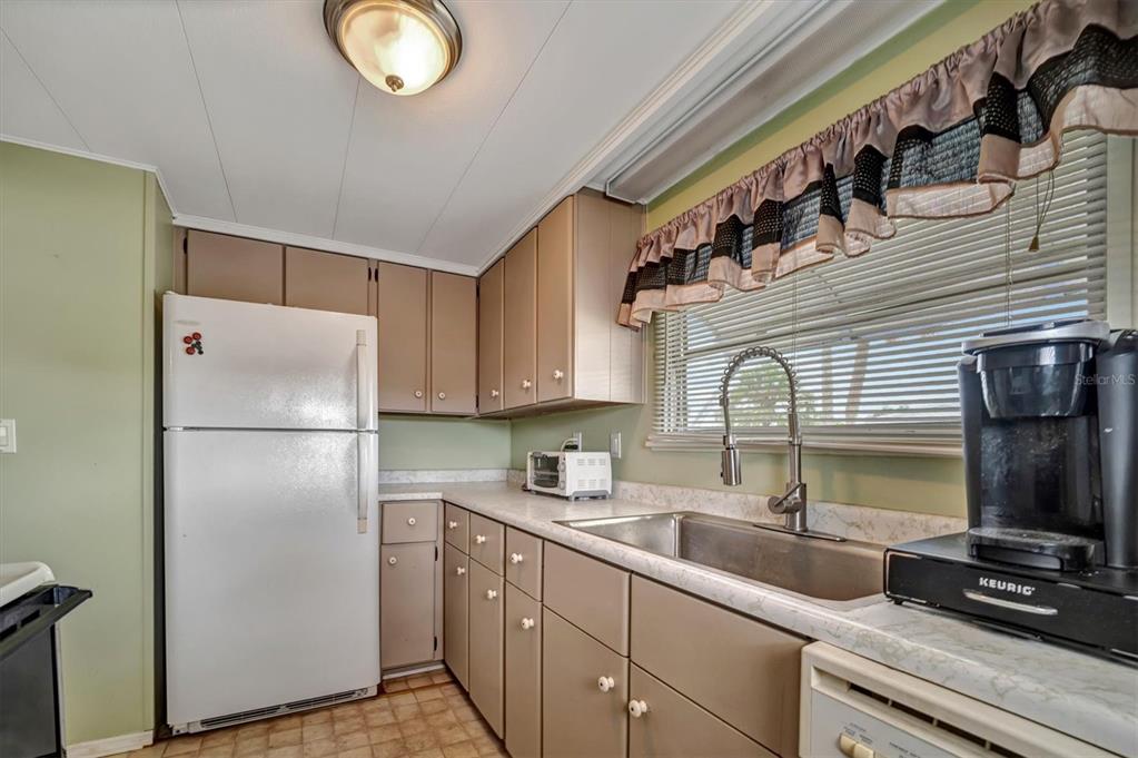A kitchen features light brown cabinets, a white refrigerator, a stainless steel sink, and countertops — 122 E SAINT ANNES CIRCLE, APOLLO BEACH, FL