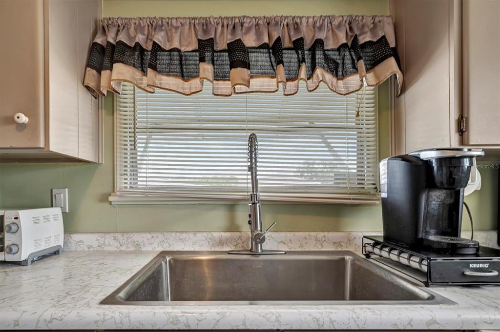 A kitchen sink with a stainless steel faucet sits below a window with a valance — 122 E SAINT ANNES CIRCLE, APOLLO BEACH, FL