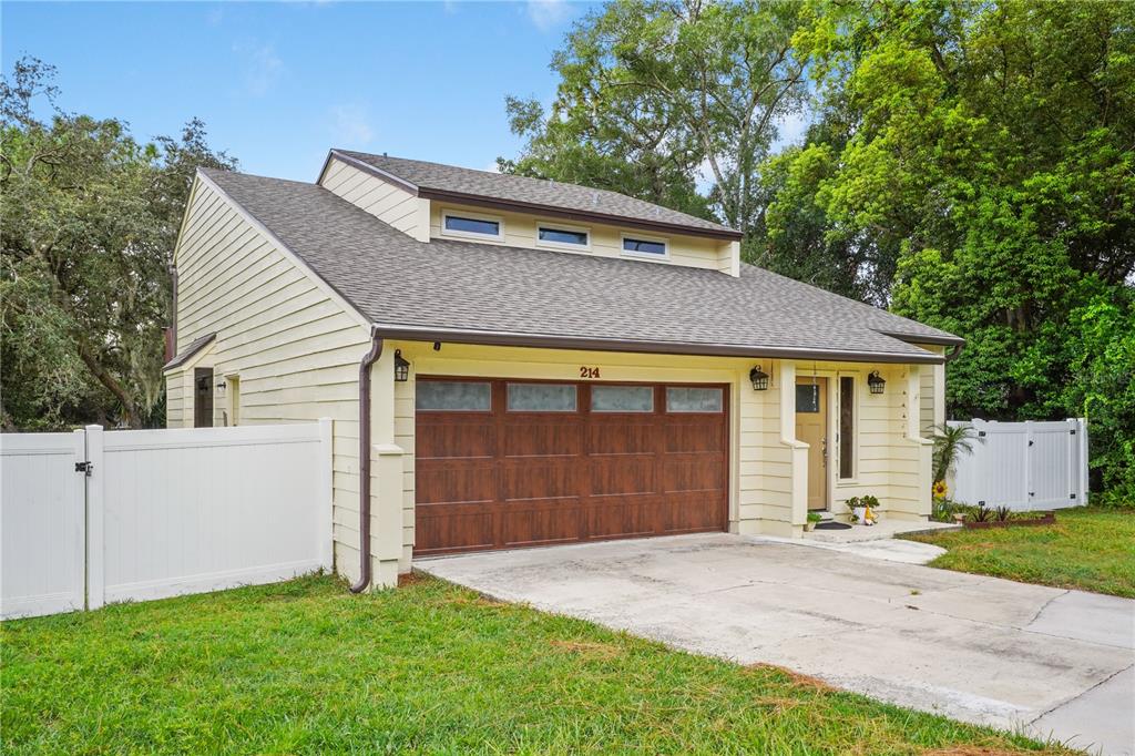 A light yellow house with a brown garage door and a dormer roof — 214 PEMBROOK PLACE, LONGWOOD, FL
