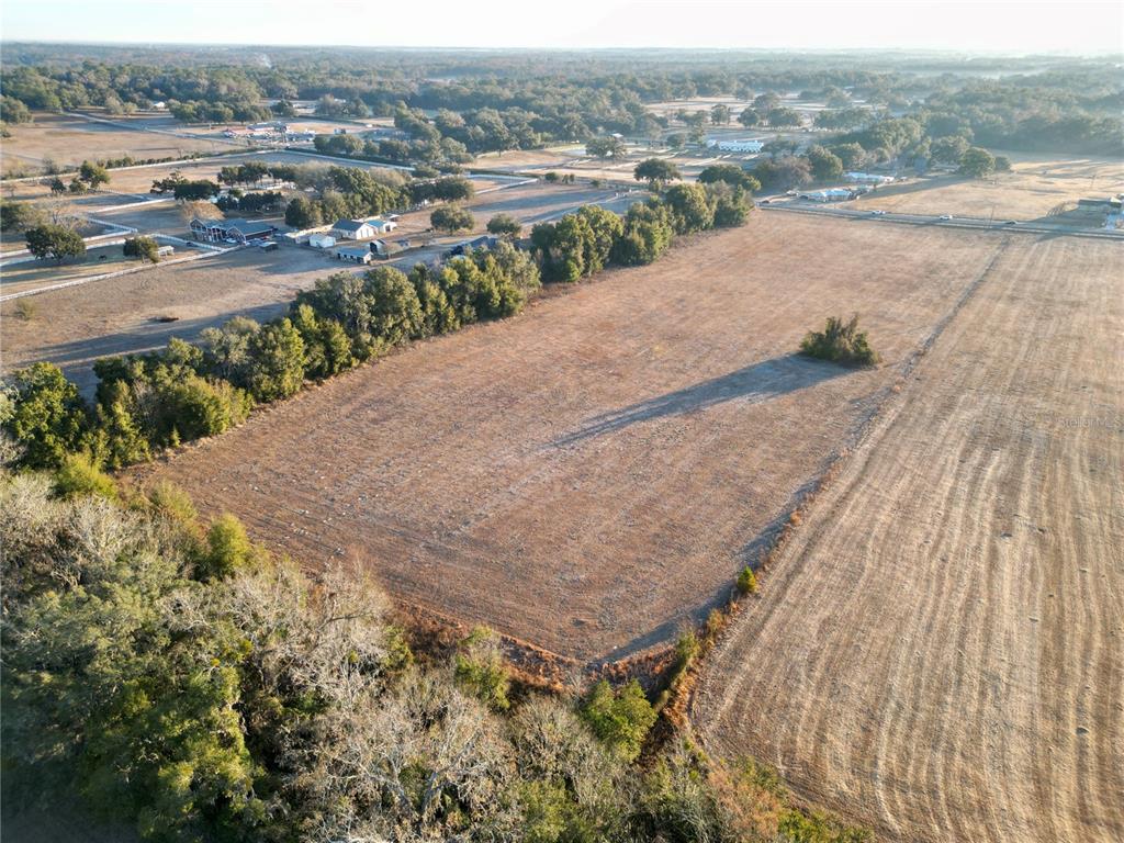 An aerial view shows a large, dry, rectangular field bordered by trees and rural properties — TBD NW HWY 225A, OCALA, FL