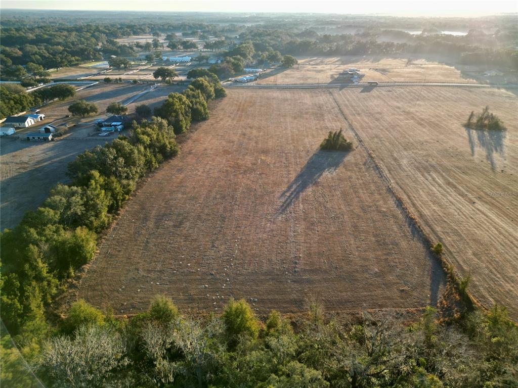 An aerial view shows a large, rectangular, cleared field bordered by trees and rural properties — TBD NW HWY 225A, OCALA, FL