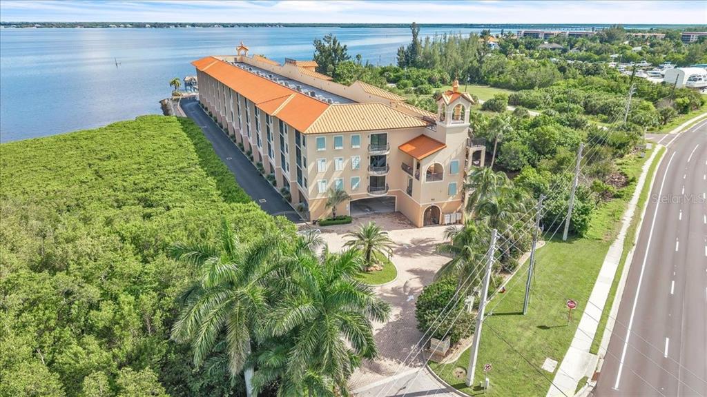 An aerial view of a multi-story building with a tile roof situated near the water — 900 E MARION AVENUE UNIT 1310, PUNTA GORDA, FL