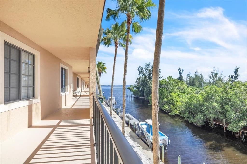 A covered balcony overlooks a canal with docked boats and palm trees — 900 E MARION AVENUE UNIT 1310, PUNTA GORDA, FL