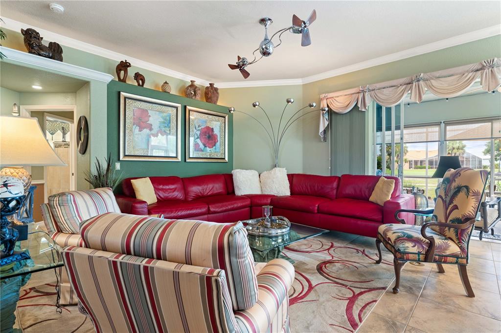 A living room features a red sectional sofa, striped armchairs, and a large arched lamp — 10309 WINDSONG ROAD, PUNTA GORDA, FL