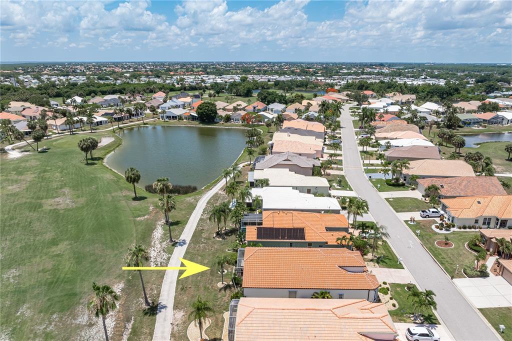 An aerial view of a suburban neighborhood featuring houses with tile roofs near a lake — 10309 WINDSONG ROAD, PUNTA GORDA, FL