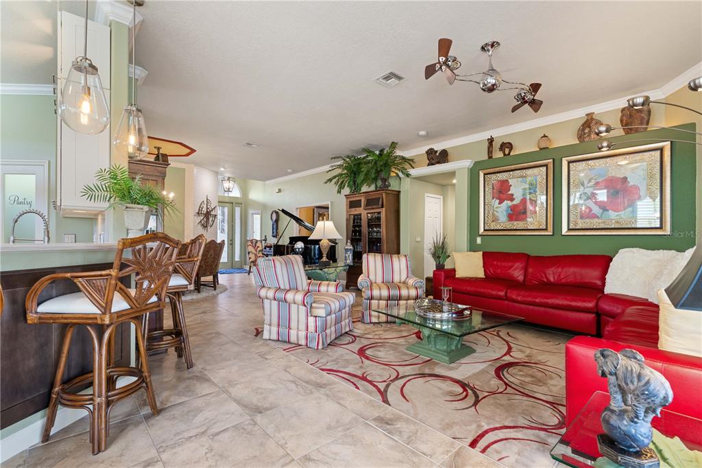 A living room with a red leather sofa, striped armchairs, and a glass coffee table — 10309 WINDSONG ROAD, PUNTA GORDA, FL