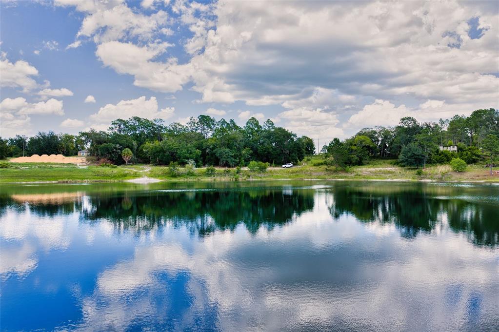 A calm lake reflects the blue sky and clouds in front of a wooded shoreline — MALAUKA LOOP, OCKLAWAHA, FL