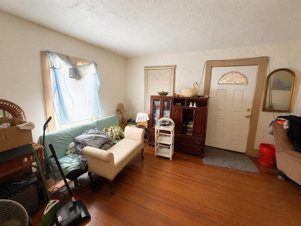 A living room features hardwood floors, a light blue sofa, a wooden cabinet, and an entryway — 202 SHADY PLACE, DAYTONA BEACH, FL