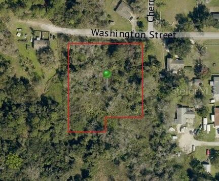 An aerial map view shows a vacant, wooded lot outlined in red near a street — 0.5 WASHINGTON STREET, NEW SMYRNA BEACH, FL
