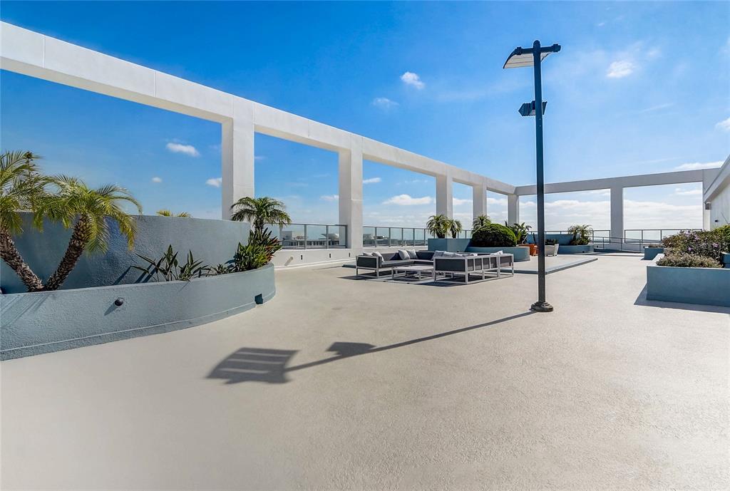 A spacious rooftop terrace features modern outdoor seating, potted palm trees, and a tall light pole — 260 S OSCEOLA AVENUE UNIT 1203, ORLANDO, FL