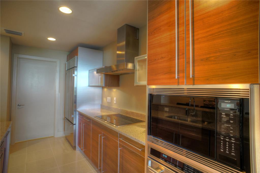 A modern kitchen features wood-grain cabinets, stainless steel appliances, and granite countertops — 260 S OSCEOLA AVENUE UNIT 1203, ORLANDO, FL