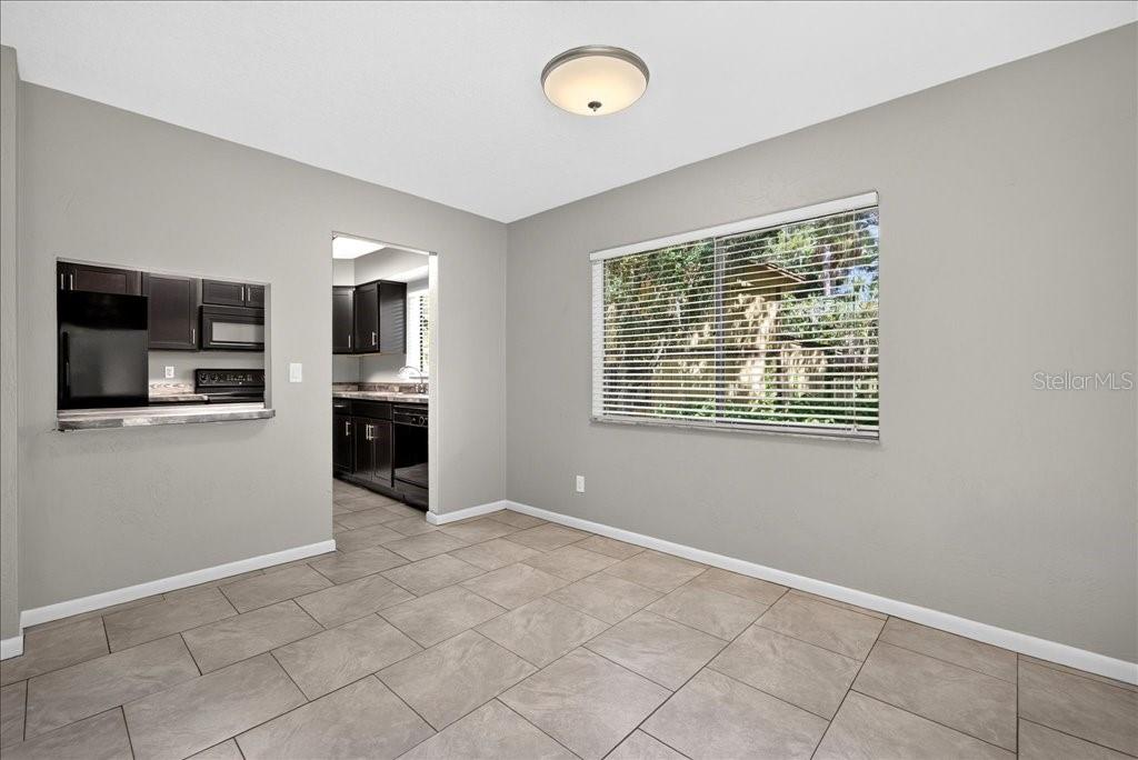 A dining area with tile flooring, a large window, and a pass-through to the kitchen — 5 GLEN ARBOR PARK, ORMOND BEACH, FL