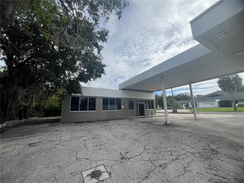 A low-rise commercial building with a large drive-thru canopy and a cracked asphalt parking lot — 1327 E SILVER SPRINGS BOULEVARD, OCALA, FL