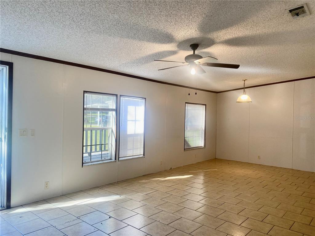 An empty room with white walls, tiled floors, a ceiling fan, and several windows — 9220 DAN LYNN STREET, BROOKSVILLE, FL