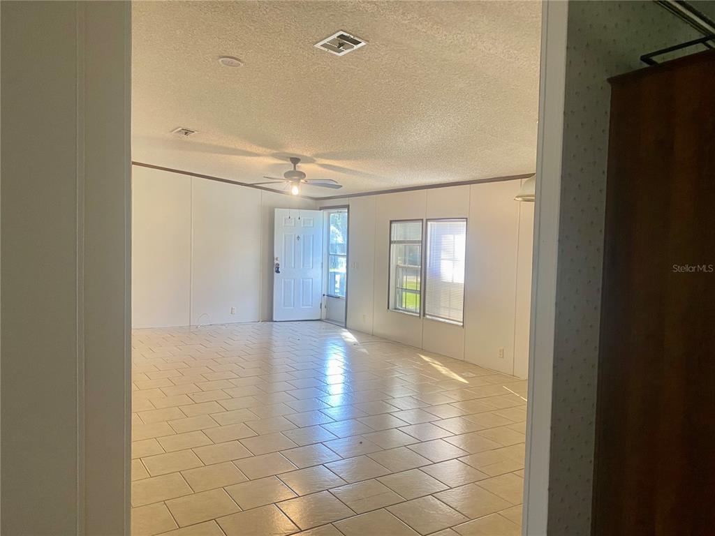 An interior view of a living room with tiled floors, white walls, and a ceiling fan — 9220 DAN LYNN STREET, BROOKSVILLE, FL