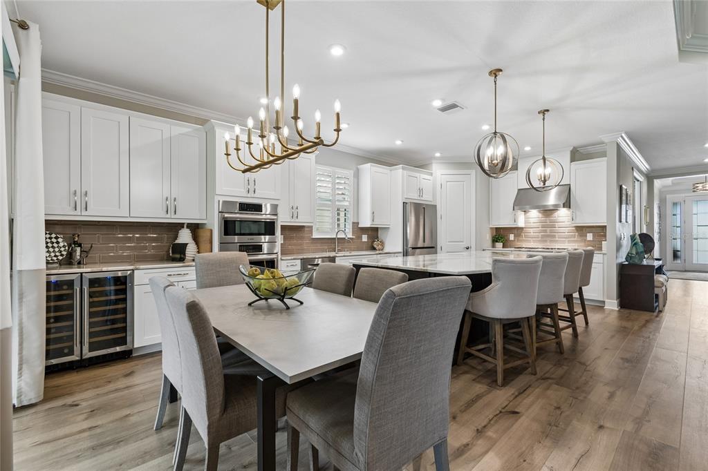 A kitchen features white cabinetry, a large island with bar seating, and a dining area — 29534 GINNETTO DRIVE, WESLEY CHAPEL, FL