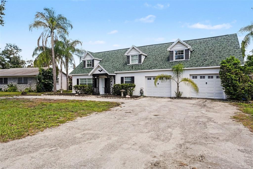 A white brick house with a green shingled roof and a large gravel driveway — 404 CLARISSA DRIVE, BRANDON, FL
